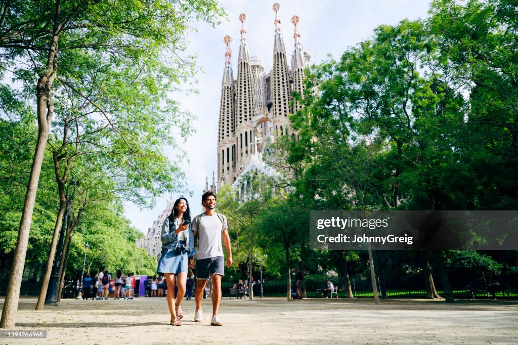 Smiling vacationers holding hands and walking in Barcelona