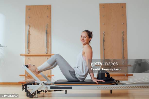woman sitting on pilates reformer - reformer stock pictures, royalty-free photos & images