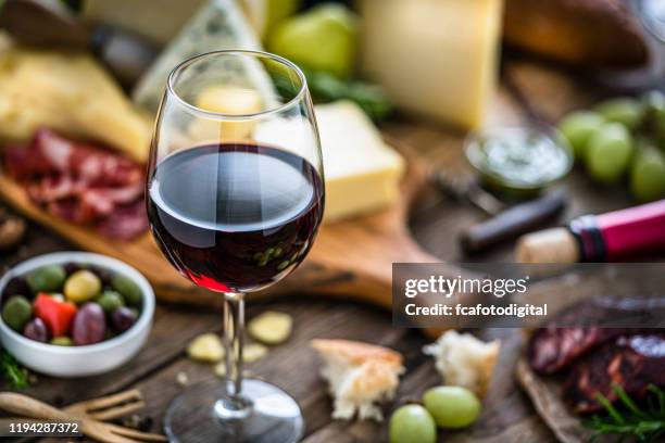aperitivo: copa de vino tinto, queso y chorizo español sobre mesa de madera rústica - queso español fotografías e imágenes de stock