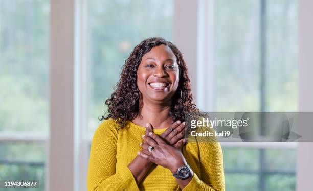 成熟したアフリカ系アメリカ人女性、笑顔 - 胸に手を当てる ストックフォトと画像
