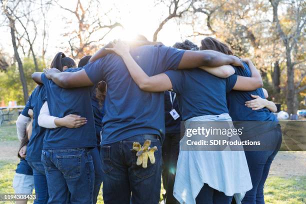 voluntarios se apiñan durante el día de limpieza de la comunidad - abrazo de grupo fotografías e imágenes de stock