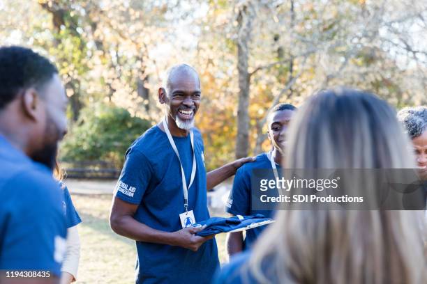 mature charity event organizer talks with volunteers - charity and relief work stock pictures, royalty-free photos & images