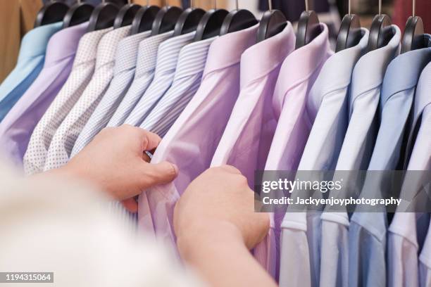 cropped hand of man choosing men's shirts in clothing store - ワイシャツ ストックフォトと画像