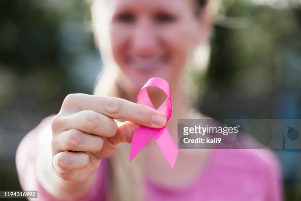 junge frau in rosa mit brustkrebs bewusstsein band - sensibilisierung für brustkrebs stock-fotos und bilder