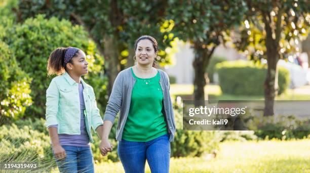 mother and daughter taking a walk, holding hands - suburban family stock pictures, royalty-free photos & images