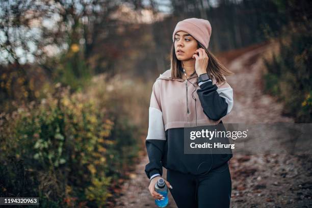 young woman is walking in nature - in ear headphones stock pictures, royalty-free photos & images