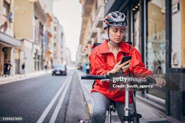 young delivery woman standing on the street - bike messenger stock pictures, royalty-free photos & images