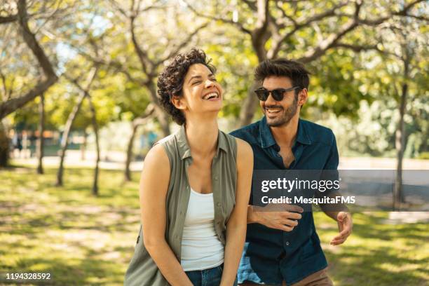 young couple enjoying the sunny day at park - hispanic couple stock pictures, royalty-free photos & images