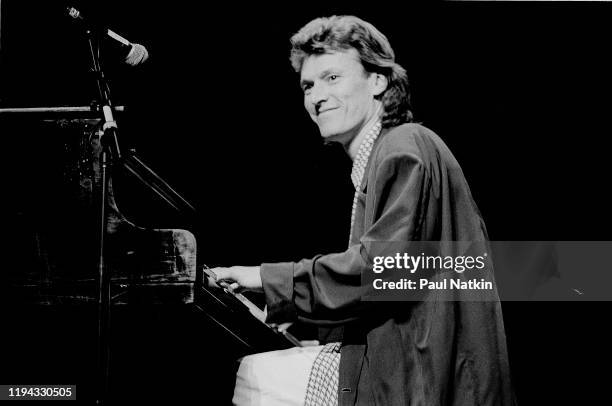 English Rock and Pop musician Steve Winwood plays keyboards as he performs onstage at the Poplar Creek Music Theater, Hoffman Estates, Illinois,...