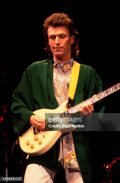 English Rock and Pop musician Steve Winwood plays guitar as he performs onstage at the UIC Pavilion, Chicago, Illinois, November 7, 1986.