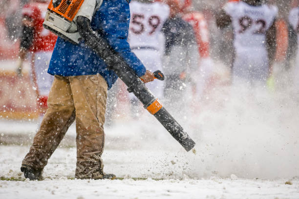 Member of the Kansas City Chiefs grounds crew uses a blower to clear heavy snow off yard lines during the fourth quarter against the Denver Broncos...