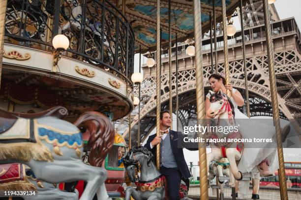 newly married white young couple riding on a paris carousel - couple paris stock-fotos und bilder