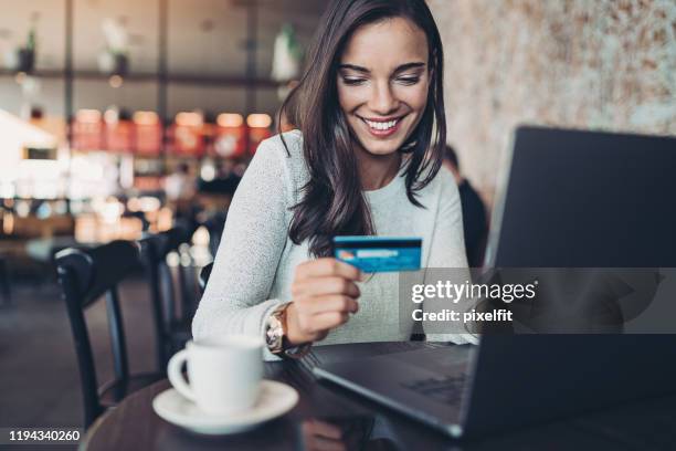 donna sorridente che effettua un acquisto con carta di credito - buy online foto e immagini stock
