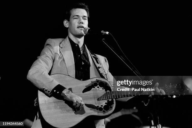 American Country musician Randy Travis plays guitar as he performs onstage at an unspecified nightclub, Dallas, Texas, December 13, 1986.