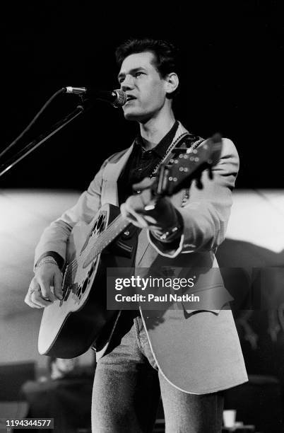 American Country musician Randy Travis plays guitar as he performs onstage at an unspecified nightclub, Dallas, Texas, December 13, 1986.