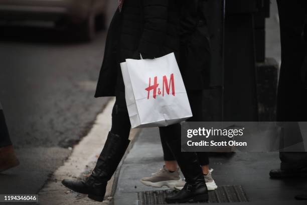 Shopper walks along the Magnificent Mile with a bag of merchandise from H&M on December 16, 2019 in Chicago, Illinois. Stock in the fashion retailer...