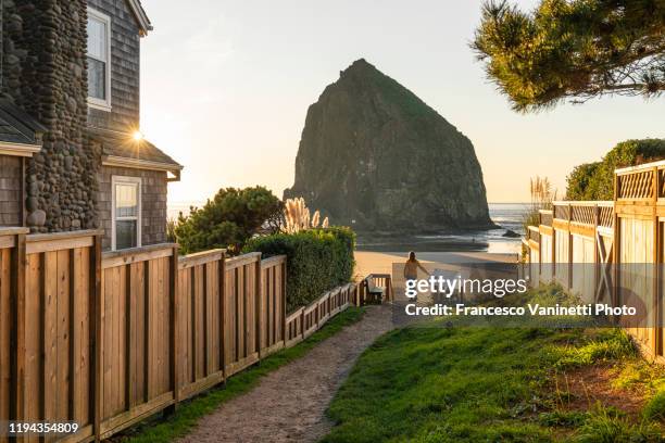 woman looking at haystack rock, cannon beach, oregon, usa. - cannon beach stock pictures, royalty-free photos & images