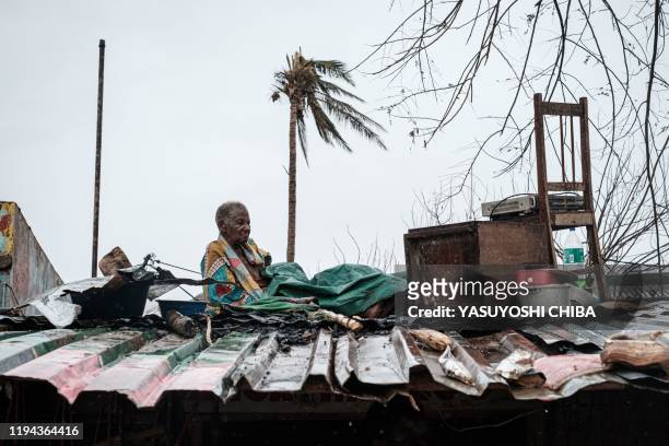 Manduana Manaque stays on a roof under the rain with her belongings in Buzi, on March 23 after the area was hit by the Cyclone Idai. - The death toll...