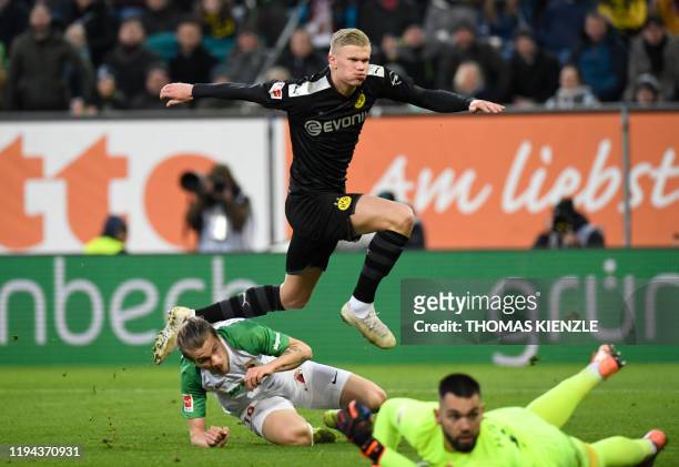 Dortmund's Norwegian forward Erling Braut Haaland jumps over Augsburg's Czech goalkeeper Tomas Koubek and Croatian defender Tin Jedvaj after he...