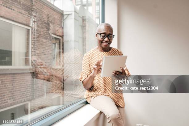 lächelnde seniorin liest zeitung - adults and pills stock-fotos und bilder
