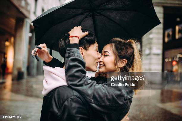 jonge mode liefhebbers aan het begin van liefdesverhaal - rain kiss stockfoto's en -beelden