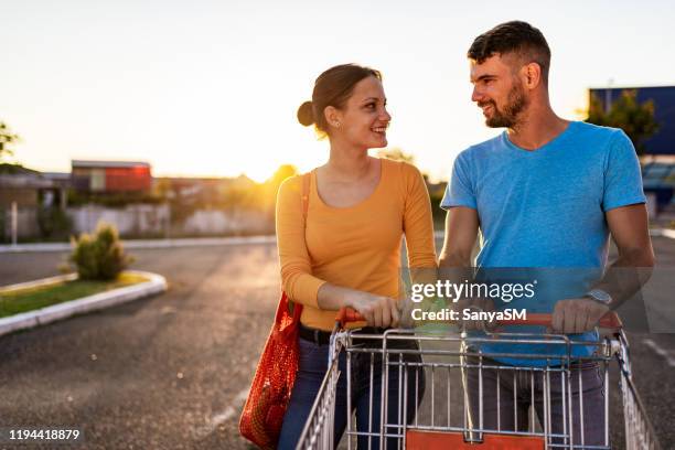 young couple after grocery shopping - man pushing cart fun play stock pictures, royalty-free photos & images