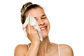 Young happy woman cleaning her face with wet wipe on white background