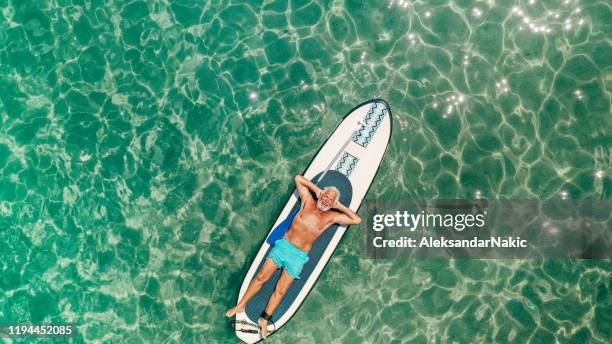 senior man relaxing on a paddleboard - top view lying down stock pictures, royalty-free photos & images