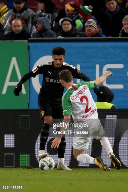 Jadon Sancho of Borussia Dortmund and Stephan Lichtsteiner of FC Augsburg battle for the ball during the Bundesliga match between FC Augsburg and...