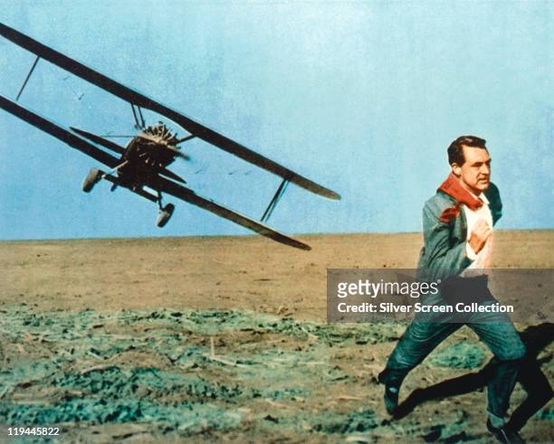 Cary Grant running as he comes under attack from a biplane under attack in an iconic scene issued as a publicity still for the film, 'North by...