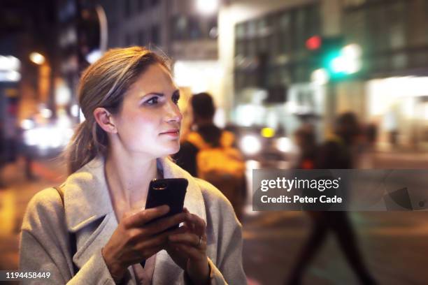 lady in the city at night with her phone - england media access stock pictures, royalty-free photos & images