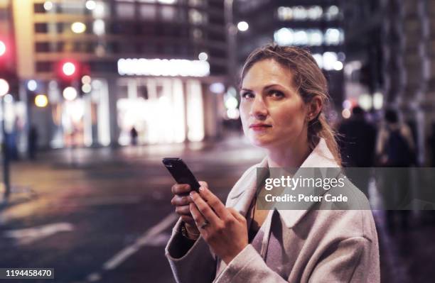 lady in the city at night with her phone - england media access stock pictures, royalty-free photos & images