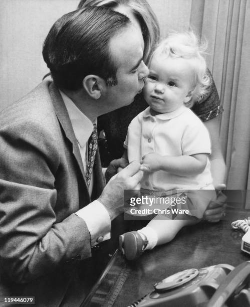 Australian media mogul Rupert Murdoch with his 14-month old daughter Elisabeth at their home in Sussex Gardens, London, 4th October 1969. Behind them...