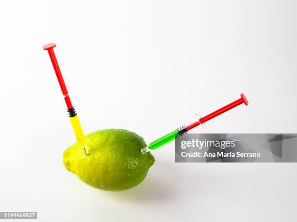 lime with syringes nailed with green and yellow substance on white background. - 食品添加物 ストックフォトと画像