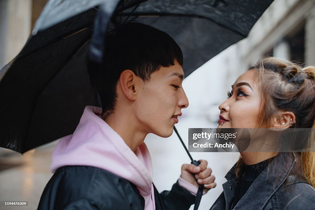 Boyfriend embracing his girlfriend under an umbrella