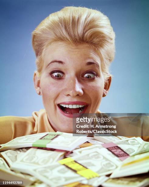 1980s SURPRISED AMAZED BUG-EYED BLONDE WOMAN LOOKING AT PILE OF CASH MONEY