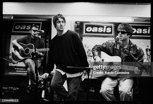 British rock band Oasis performing live at an in-store promotion gig, UK, 1994; they are Paul Arthurs, Liam Gallagher, Noel Gallagher.