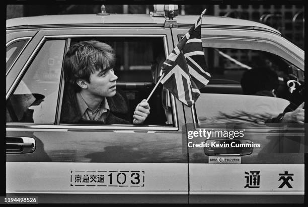 British singer-songwriter Damon Albarn of rock band Blur holding a Union Jack flag while travelling on a taxi in Tokyo, Japan, March 1992.