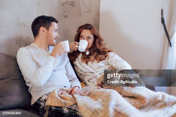 husband and wife relaxing on the couch - couple pyjamas stock pictures, royalty-free photos & images