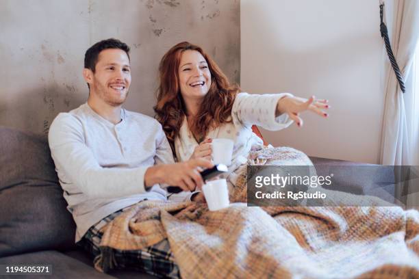 husband and wife watching tv on their cozy sofa - couple couch imagens e fotografias de stock