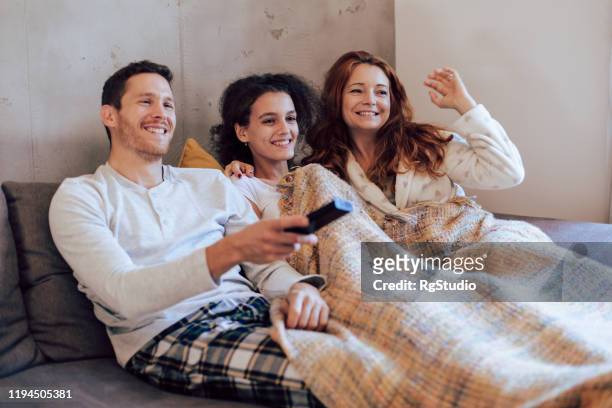 family enjoying on the sofa and watching tv - blanket stock pictures, royalty-free photos & images