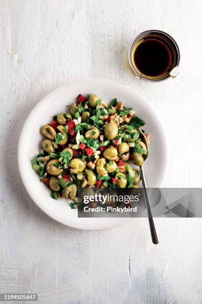 aceitunas verdes y nueces, surtido de aceitunas en plato con aceite, aceitunas verdes, ensalada de aceitunas - green olive fotografías e imágenes de stock