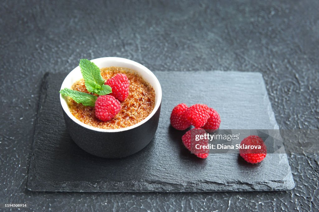 Creme brulee or catalana with raspberries . Traditional French, Spanish and Italian vanilla cream dessert with caramelized brown sugar.
