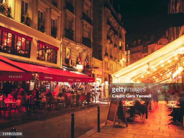 busy paris street lined with bars and restaurants - french cafe stock pictures, royalty-free photos & images