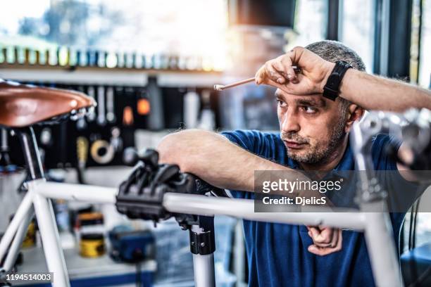 tired bicycle mechanic taking a break. - frustrated workman stock pictures, royalty-free photos & images