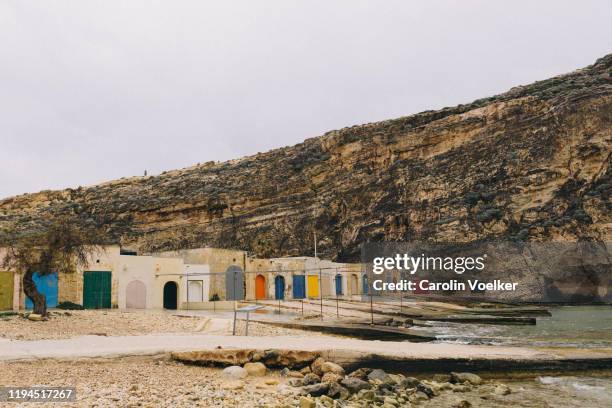 fishing huts with brightly coloured doors on the shore of the inland sea, san lawrenz, gozo, malta - azure window malta stock pictures, royalty-free photos & images