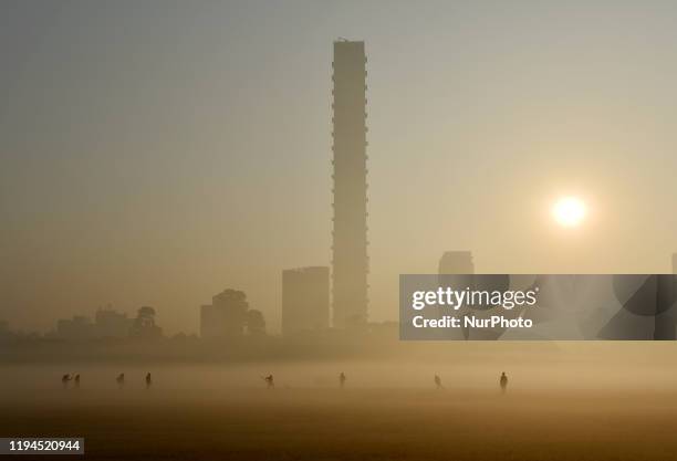 Boys play cricket on a foggy field in Kolkata, India, 18 January, 2020.