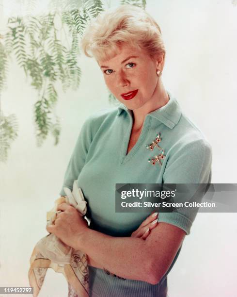 Doris Day, US actress and singer, wearing a light blue, short-sleeved woollen blouse, with two dragonfly brooches, circa 1955.