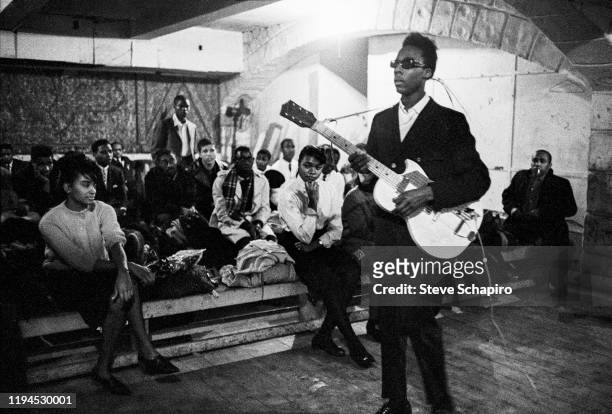 View of an unidentified musician with a guitar and sunglasses as he waits backstage, with other performers, at the Apollo Theater, New York, New...