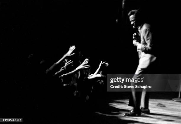 Audience members reach out their arms as an unidentified singer performs on stage at the Apollo Theater, New York, New York, early 1960s.